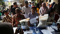 Warga mengantre dengan tertib untuk mendapatkan beras yang disalurkan Perum Bulog.