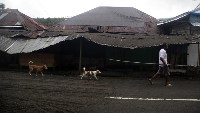 Warga melintas di depan rumah yang rusak akibat erupsi Gunung Ruang di Tagulandang, Kabupaten Kepulauan Sitaro, Sulawesi Utara, Kamis (2/5/2024). BPBD mencatat sebanyak 3.614 unit rumah mengalami kerusakan di Tagulandang yang tersebar di dua kelurahan dan 13 kampung akibat erupsi Gunung Ruang. ANTARA FOTO/Andri Saputra/nym.