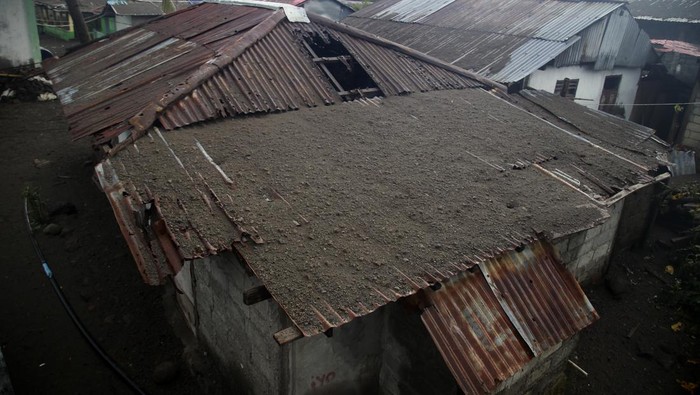 Warga melintas di depan rumah yang rusak akibat erupsi Gunung Ruang di Tagulandang, Kabupaten Kepulauan Sitaro, Sulawesi Utara, Kamis (2/5/2024). BPBD mencatat sebanyak 3.614 unit rumah mengalami kerusakan di Tagulandang yang tersebar di dua kelurahan dan 13 kampung akibat erupsi Gunung Ruang. ANTARA FOTO/Andri Saputra/nym.