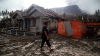 Warga berjalan di depan rumah yang rusak parah terdampak erupsi Gunung Ruang di Desa Laingpatehi Pulau Ruang, Kabupaten Kepulauan Sitaro, Sulawesi Utara.