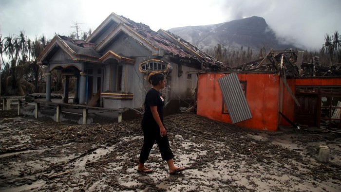 Warga berjalan di depan rumah yang rusak parah terdampak erupsi Gunung Ruang di Desa Laingpatehi Pulau Ruang, Kabupaten Kepulauan Sitaro, Sulawesi Utara, Jumat (3/5/2024). Dua desa yang berada di bawah kaki Gunung Ruang yaitu Desa Laingpatehi dan Desa Pumpente menjadi desa paling parah terkena dampak letusan Gunung Ruang dan puluhan rumah di lokasi tersebut tertimbun material abu vulkanik. ANTARA FOTO/Andri Saputra/aww.