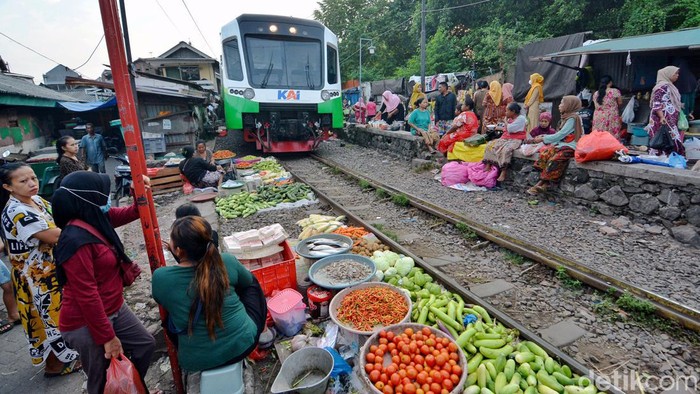 Surabaya- Sejumlah warga nekat melakukan aktivitas jual beli di perlintasan rel kereta api di Pasar Ekstrem Dupak Bangunsari, Surabaya, Minggu (5/5/2024). Setiap pagi sedikitnya tiga sampai empat kereta api yang melintas.
