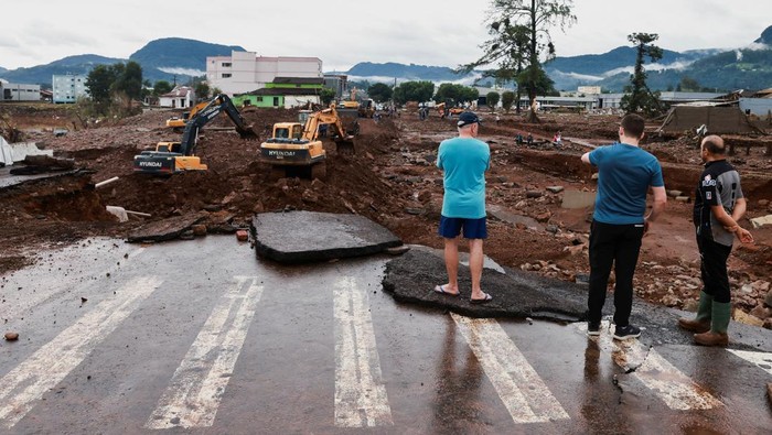 Penampakan Jalan-jalan di Brasil Hancur Diterjang Banjir People stand by a road destroyed by the floods at Roca Sales in Rio Grande do Sul, Brazil, May 4, 2024. REUTERS/Diego Vara