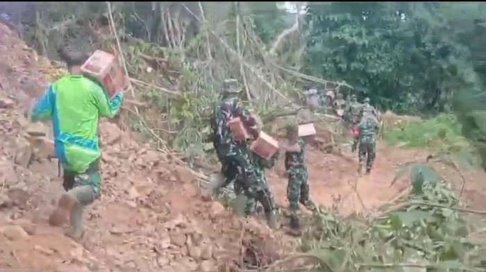 Personel TNI berjalan kaki membawa bantuan untuk korban longsor di Luwu.