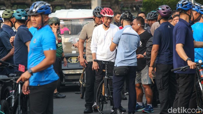 Presiden Joko Widodo (Jokowi) tengah menyapa warga saat bersepeda di hari bebas kendaraan atau car free day (CFD) di sekitar Bundaran HI, Jakarta, Minggu (5/5/2024). Jokowi nampak diserbu warga yang tengah berolahraga di Bundaran HI.