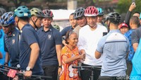 Jokowi menyalami warga sambil foto bersama di sela-sela aktivitas bersepedanya.