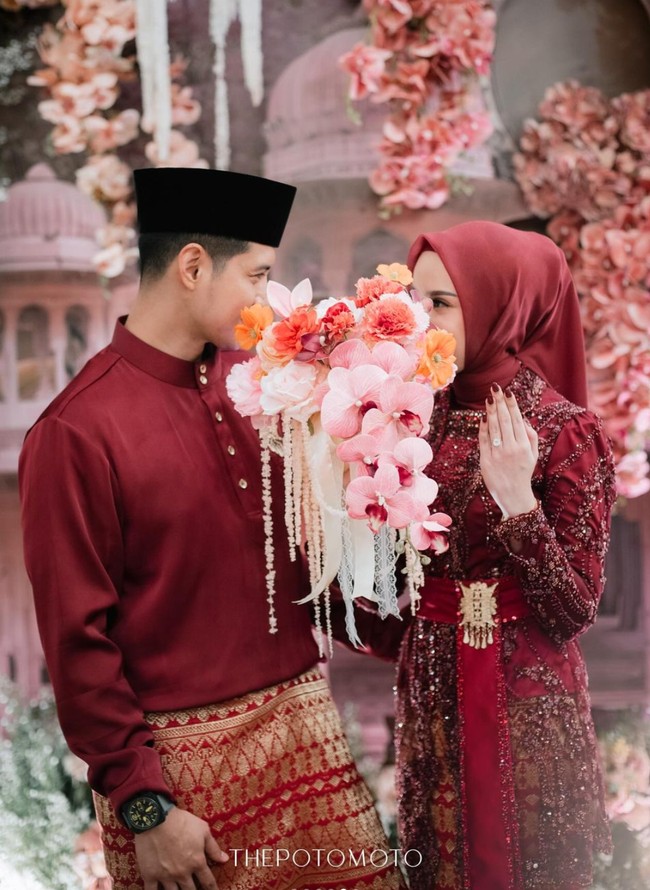 Di momen lamarannya itu Chand dan Dea memilih kompak mengenakan busana berwarna merah marun. Pria 39 tahun itu tampil gagah mengenakan busana bernuansa Melayu. Ia memadukan atasan lengan panjang berkancing celana panjang dan kain songket berwarna senada. Sementara Dea tampil anggun dengan kebaya brukat dipadukan dengan kain songket dan hijab senada. Foto: Instagram/@chand_kelvin