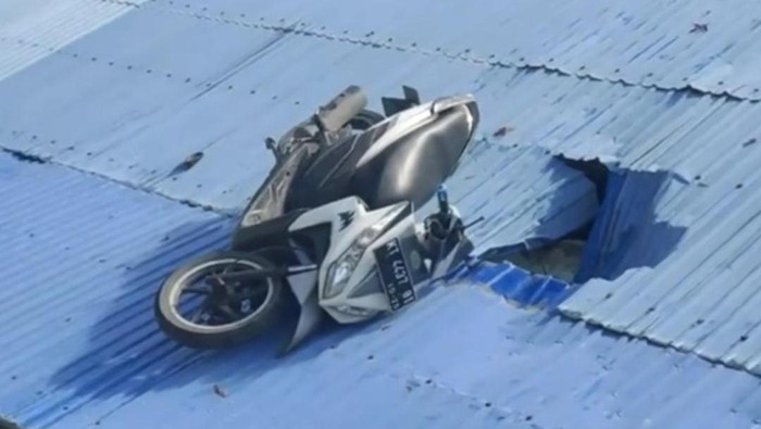 Motor nyangkut di atap rumah.