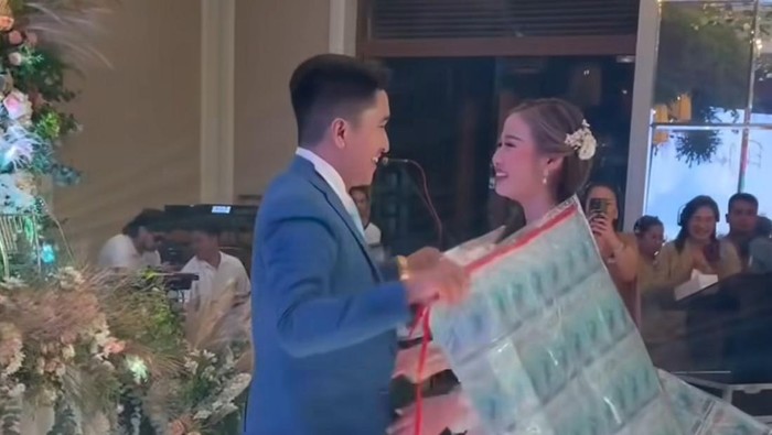 Pengantin pria ini memberikan karpet uang tunai untuk pengantin wanita di hari pernikahannya. Momen tersebut langsung viral di media sosial
