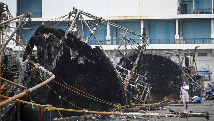 Potret Bangkai Kapal Nelayan Muara Baru yang Terbakar Pekerja menggunakan sampan melintas di depan bangkai kapal yang hangus terbakar di Pelabuhan Muara Baru, Jakarta, Senin (6/5/2024). Setelah dinyatakan padam oleh Suku Dinas Penanggulangan Kebakaran dan Penyelamatan (Gulkarmat) Jakarta Utara pada, Minggu (5/5) malam, satu dari tiga bangkai kapal kembali terbakar pada, Senin (6/6) pagi akibat hembusan angin dan sebagian besar kapal itu berbahan fiber yang mudah terbakar. ANTARA FOTO/Erlangga Bregas Prakoso/YU