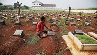 Warga sedang membersihkan nisan di TPU yang berada di pinggir gerbang tol Setu Utara 2.