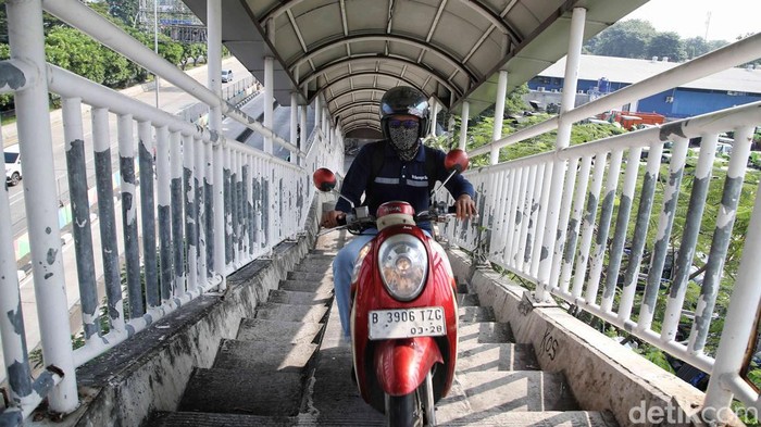 Sejumlah pengendara motor melintas di jembatan penyebrangan orang (JPO) untuk pejalan kaki di jalan Yos Sudarso, Jakarta Utara, Selasa (7/5/2024).