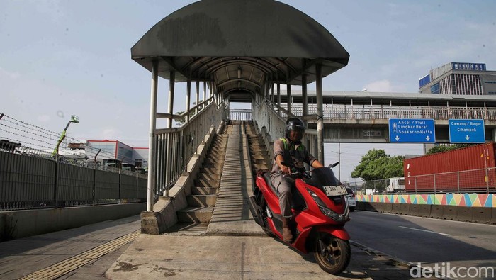 Sejumlah pengendara motor melintas di jembatan penyebrangan orang (JPO) untuk pejalan kaki di jalan Yos Sudarso, Jakarta Utara, Selasa (7/5/2024).