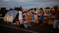 Sejumlah orang melipat selimut saat mereka berkemah di jalan dekat jalan yang banjir di Eldorado do Sul, di Rio Grande do Sul, Brasil, Senin (6/5/2024). Hujan lebat di negara bagian paling selatan Brazil, Rio Grande do Sul, telah menyebabkan kekacauan.