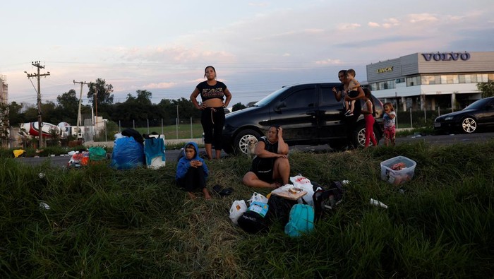 Men fold a blanket as they camp on the road near a flooded street in Eldorado do Sul, in Rio Grande do Sul, Brazil, May 6, 2024. REUTERS/Amanda Perobelli