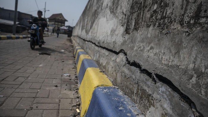 Warga berjalan di tanggul pengaman pantai yang retak di kawasan pesisir Kalibaru, Cilincing, Jakarta, Selasa (7/5/2024). Tanggul yang berfungsi mengurangi dampak banjir rob dan rembesan air laut sekitar Cilincing itu mengalami keretakan sehingga dapat membahayakan warga yang beraktivitas di kawasan tersebut. ANTARA FOTO/Aprillio Akbar/rwa.