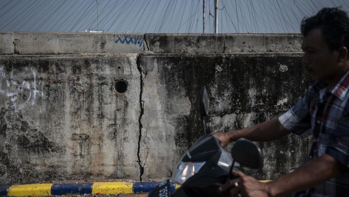 Warga berjalan di tanggul pengaman pantai yang retak di kawasan pesisir Kalibaru, Cilincing, Jakarta, Selasa (7/5/2024). Tanggul yang berfungsi mengurangi dampak banjir rob dan rembesan air laut sekitar Cilincing itu mengalami keretakan sehingga dapat membahayakan warga yang beraktivitas di kawasan tersebut. ANTARA FOTO/Aprillio Akbar/rwa.