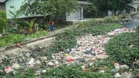 Seorang anak bermain sepeda di samping kali Kawasan Pulo Sirih, Cikarang, Rabu (8/5/2024).