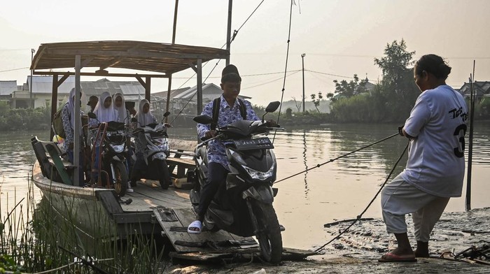 Siswa di Muara Gembong Gunakan Eretan untuk Berangkat Sekolah Sejumlah siswa menaiki eretan menyeberangi Sungai Citarum di kawasan Desa Pantai Bahagia, Muara Gembong, Kabupaten Bekasi, Jawa Barat, Selasa (8/5/2024). Para siswa menggunakan eretan sebagai moda penyeberangan menuju sekolah dengan tarif Rp2 ribu guna mempersingkat jarak tempuh karena minimnya akses jembatan penyebarangan di wilayah tersebut. ANTARA FOTO/Sulthony Hasanuddin/foc.