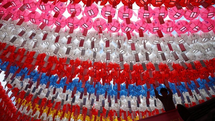 A woman prays underneath lotus lanterns attached to prayer petitions at Jogye temple in Seoul, South Korea, May 8, 2024. REUTERS/Kim Hong-Ji