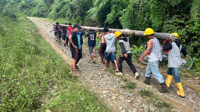 Petugas PLN Sidrap bersama warga menggotong tiang untuk perbaikan jaringan di wilayah terdampak banjir.