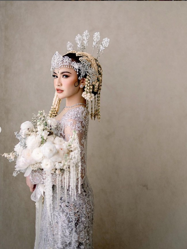 Kebaya putih Mahalini tampak mewah dengan perpaduan berbagai ornamen seperti sequin, payet, kristal dan bordiran. Kebaya modern dengan garis leher heart-shaped itu dipadukan dengan kain Batik bernuansa hitam-putih. Foto: Instagram/@askyfebrianti