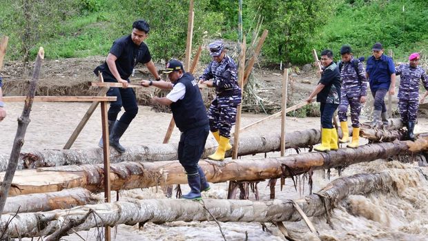 Pj Gubernur Sulsel Bahtiar Baharuddin dan Danlatamal VI Makassar Brigjen TNI (Mar) Andi Rahmat M melewati titian bambu dan seberangi sungai.