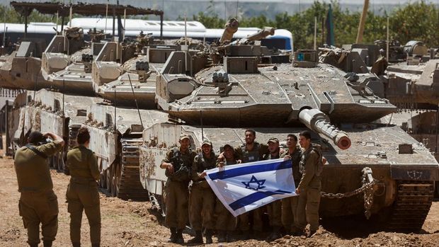 Tentara Israel berpose di samping tank, di tengah bentrok nan sedang berjalan antara Israel dan golongan Islam Palestina Hamas, dekat Perbatasan Israel-Gaza, di Israel selatan, 9 Mei 2024. (REUTERS/Amir Cohen)