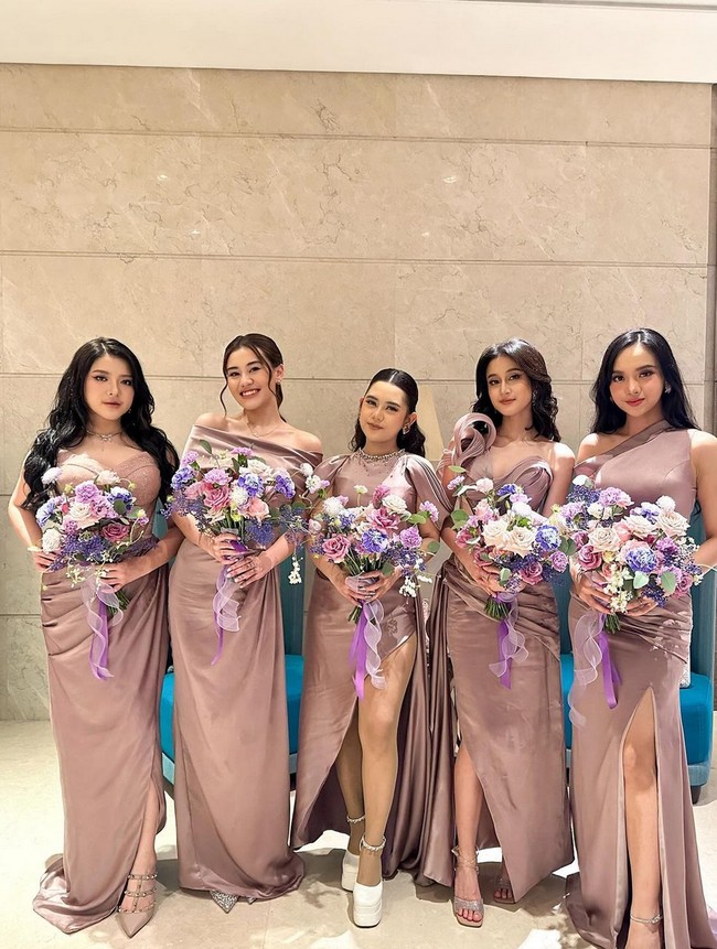 Kelima bridesmaid tampil dalam balutan gaun nuansa mauve untuk pesta resepsi. Masing-masing memegang buket bunga cantik bertema keunguan. Foto: Dok. The Bridestory, Axioo, Instagram