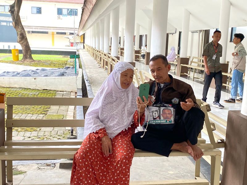 Pasutri calon jemaah haji asal Bekasi, Jabar, Misbah (62) dan Noneng (61) terlihat menahan tangisnya saat melakukan video call bersama cucu kesayangannya.