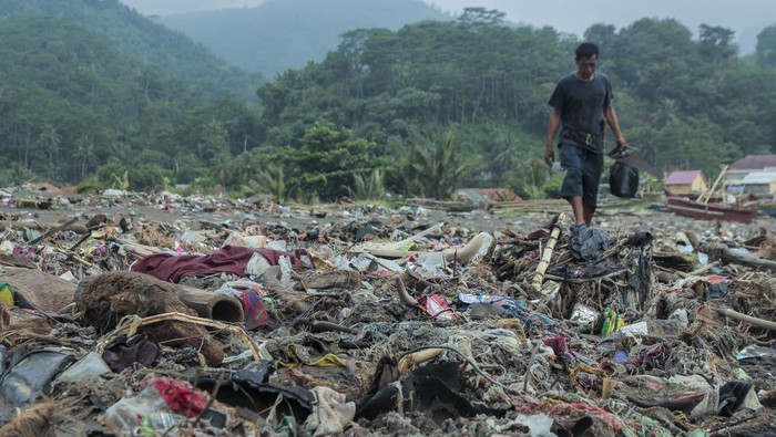 Warga melintas di sekitar tumpukan sampah di Pantai Cibutun Loji, Desa Sangrawayang, Simpenan, Kabupaten Sukabumi, Jawa Barat, Sabtu (11/5/2024). Menurut warga setempat, sudah sepekan terakhir sampah rumah tangga yang terbawa arus laut tersebut menumpuk di pesisir pantai yang selain mencemari lingkungan juga menghambat aktivitas perahu nelayan yang akan melaut. ANTARA FOTO/Henry Purba/agr/aww.