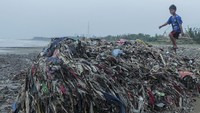 Seorang anak bermain di antara tumpukan sampah di Pantai Cibutun Loji, Desa Sangrawayang, Simpenan, Kabupaten Sukabumi, Jawa Barat, Sabtu (11/5/2024).