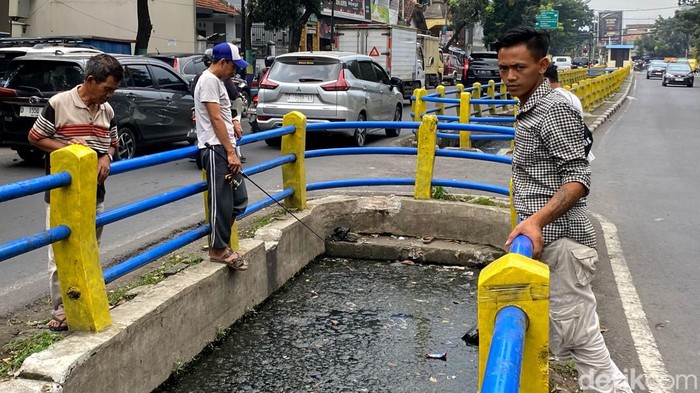 Warga memancing di saluran irigasi yang ada di Jalan Lewipanjang, Kota Bandung.