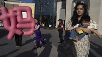 Seorang ibu menggendong anaknya di sebuah mal di Beijing, China, Sabtu (11/5/2024).