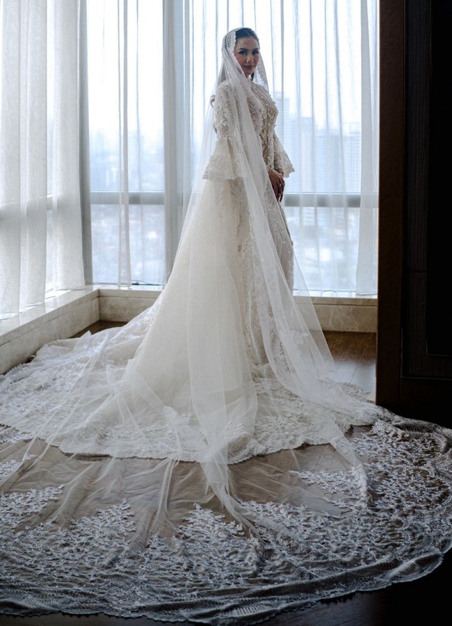Bridal robe kedua datang dari karya desainer Monica Ivena. Outer bergaya vintage klasik ini sarat akan detail dengan penerapan bordir, payet, manik-manik serta mutiara. Bridal robe semakin terlihat indah berkat lengan ruffle bervolume dan veil sepanjang 4 meter. Foto: Instagram/@axioo @thebridestory @hiantjen