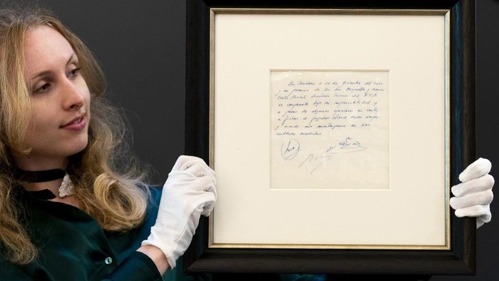 A Bonhams staff member holds up a napkin on which a written commitment was made to then 13-year-old soccer player Lionel Messi from Argentina for a contract from FC Barcelona in December 2000 is on display at Bonhams in London, England, Wednesday, May 8, 2024 before it is offered at auction. ( Jordan Pettitt/PA via AP)