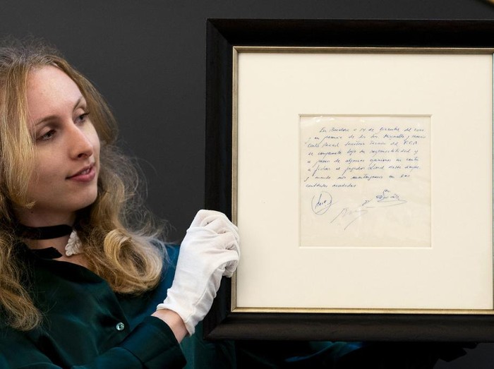 A Bonhams staff member holds up a napkin on which a written commitment was made to then 13-year-old soccer player Lionel Messi from Argentina for a contract from FC Barcelona in December 2000 is on display at Bonhams in London, England, Wednesday, May 8, 2024 before it is offered at auction. ( Jordan Pettitt/PA via AP)