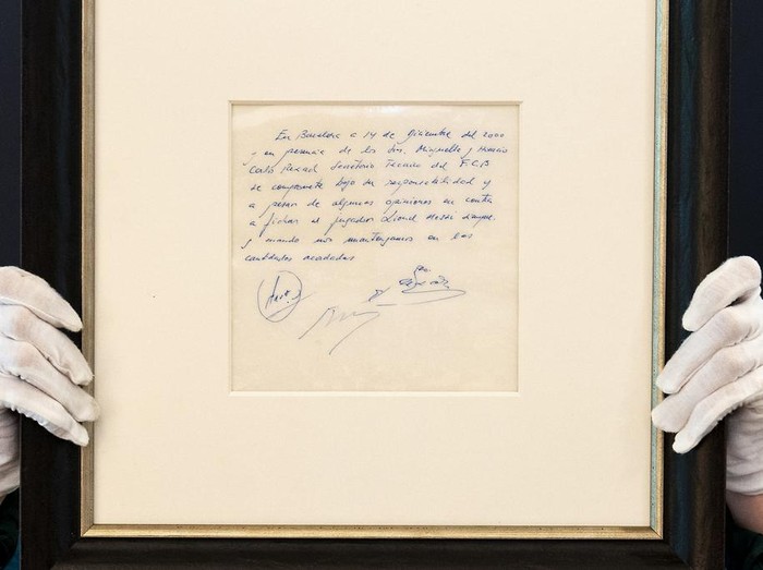 A Bonhams staff member holds up a napkin on which a written commitment was made to then 13-year-old soccer player Lionel Messi from Argentina for a contract from FC Barcelona in December 2000 is on display at Bonhams in London, England, Wednesday, May 8, 2024 before it is offered at auction. ( Jordan Pettitt/PA via AP)