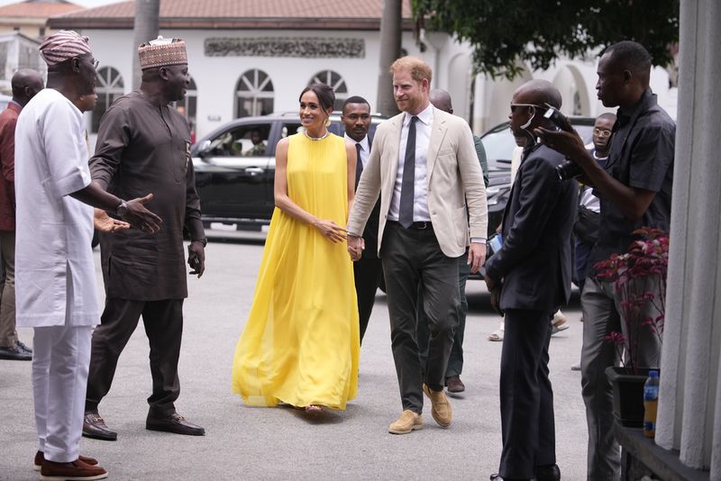 Prince Harry, left, and Meghan, right, holding hands upon arrival at the government house in Lagos Nigeria, Sunday, May 12, 2024. Prince Harry and his wife Meghan are in Nigeria to champion the Invictus Games, which Prince Harry founded to aid the rehabilitation of wounded and sick servicemembers and veterans. (AP Photo/Sunday Alamba)