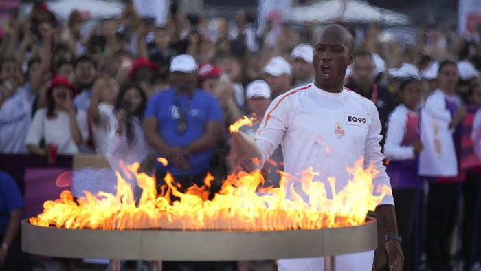Potret Meriah Estafet Obor Olimpiade Paris Torchbearer Didier Drogba of France holds the Olympic torch to light the cauldron at the Velodrome stadium in Marseille, southern France, Thursday, May 9, 2024. Torchbearers are to carry the Olympic flame through the streets of France's southern port city of Marseille, one day after it arrived on a majestic three-mast ship for the welcoming ceremony. (AP Photo/Daniel Cole)