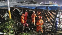 Tim penyelamat mencari korban di bawah papan reklame yang runtuh di Mumbai, India, Senin (13/5/2024).