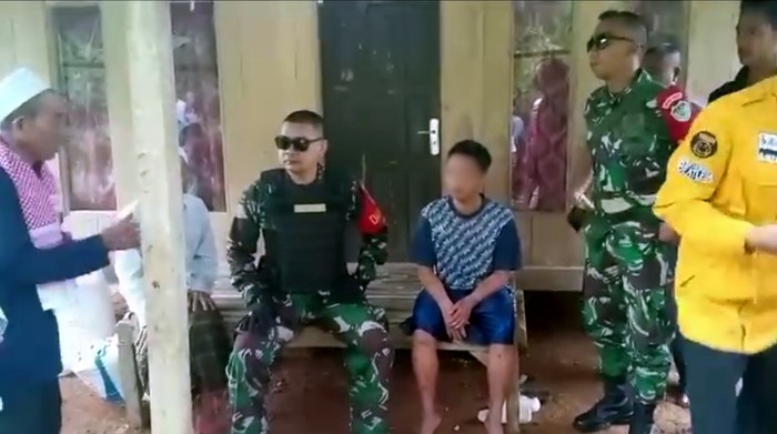 Pelaku pembunuhan ibu kandung, saat diamankan di depan rumahnya (berbaju biru)