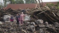 Warga berdiri diantara puing-puing bangunan yang rusak akibat banjir bandang di Agam, Sumatera Barat, Selasa (14/5/2024).