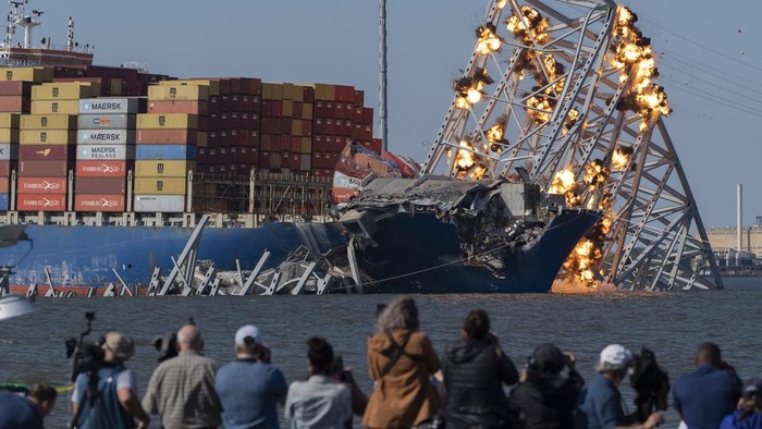 Potret Jembatan Baltimore AS Dibongkar dengan Cara Diledakkan Explosive charges are detonated to bring down sections of the collapsed Francis Scott Key Bridge resting on the container ship Dali on Monday, May 13, 2024, in Baltimore. (AP Photo/Mark Schiefelbein)