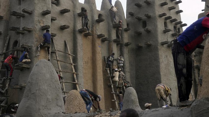 Malians take part in the annual replastering of the world's largest mud-brick building, the Great Mosque of Djenne, Mali, Sunday, May 12, 2024. The building has been on UNESCO's World Heritage in Danger list since 2016. The mosque and surrounding town are threatened by conflict. Djenne's mosque requires a new layer of mud each year before the start of the rainy season in June. (AP Photo/Moustapha Diallo)