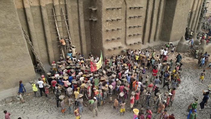 Malians take part in the annual replastering of the world's largest mud-brick building, the Great Mosque of Djenne, Mali, Sunday, May 12, 2024. The building has been on UNESCO's World Heritage in Danger list since 2016. The mosque and surrounding town are threatened by conflict. Djenne's mosque requires a new layer of mud each year before the start of the rainy season in June. (AP Photo/Moustapha Diallo)