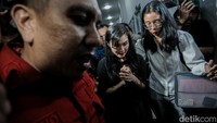 Ia mengimpitkan tangannya sambil berjalan ke mobil Innova.