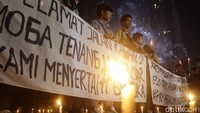 Massa aksi terlihat membawa sejumlah atribut mulai dari spanduk, foto korban hingga obor.