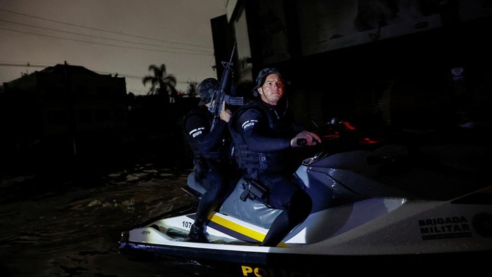 A police officer holds a rifle while patrolling on a boat in a flooded area to prevent theft in the downtown of Porto Alegre,Rio Grande do Sul state, Brazil, May 12, 2024. REUTERS/Adriano Machado