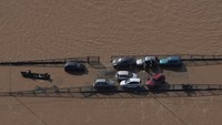Sejumlah mobil terjebak di tengah jalan yang dilanda banjir. AP/Andre Penner